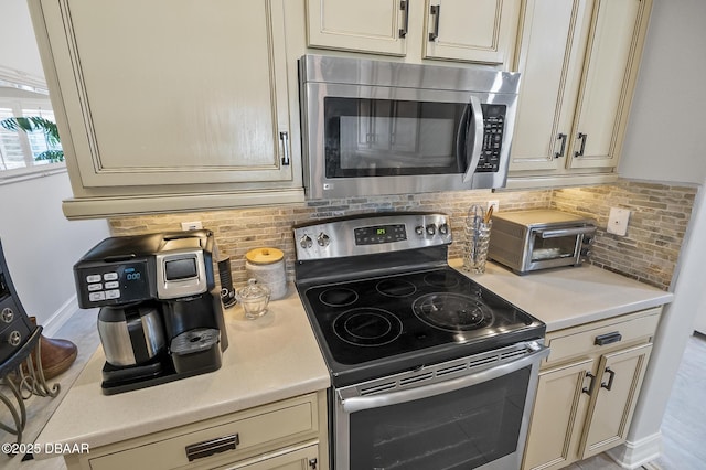 kitchen with decorative backsplash, cream cabinetry, and appliances with stainless steel finishes