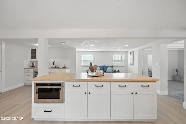 5540 W Bayshore Dr, Port Orange, FL 32127 - kitchen with butcher block counters, light wood-type flooring, white cabinetry, stainless steel oven, and open floor plan