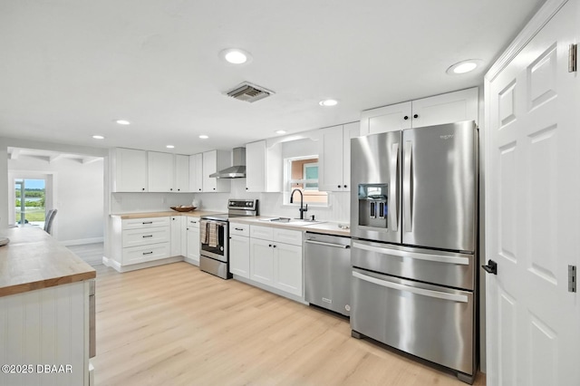 5540 W Bayshore Dr, Port Orange, FL 32127 - kitchen featuring stainless steel appliances, wall chimney range hood, light wood-style floors, wood counters, and recessed lighting