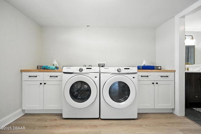 5540 W Bayshore Dr, Port Orange, FL 32127 - laundry area with washing machine and clothes dryer, light wood-type flooring, and cabinet space