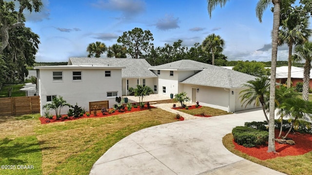 5540 W Bayshore Dr, Port Orange, FL 32127 - view of front of property with driveway, stucco siding, an attached garage, and roof with shingles