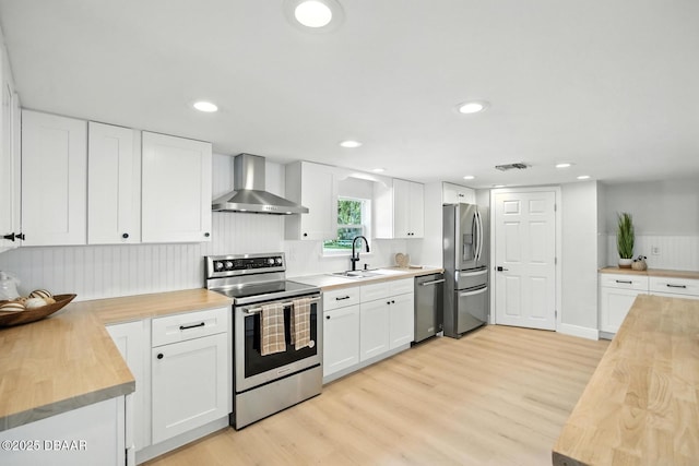 5540 W Bayshore Dr, Port Orange, FL 32127 - kitchen with stainless steel appliances, wall chimney exhaust hood, wood counters, light wood-style floors, and recessed lighting