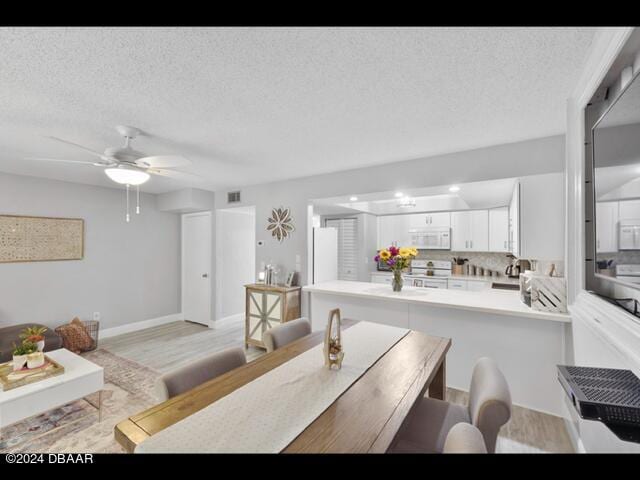 dining area with ceiling fan, a textured ceiling, and light wood-type flooring