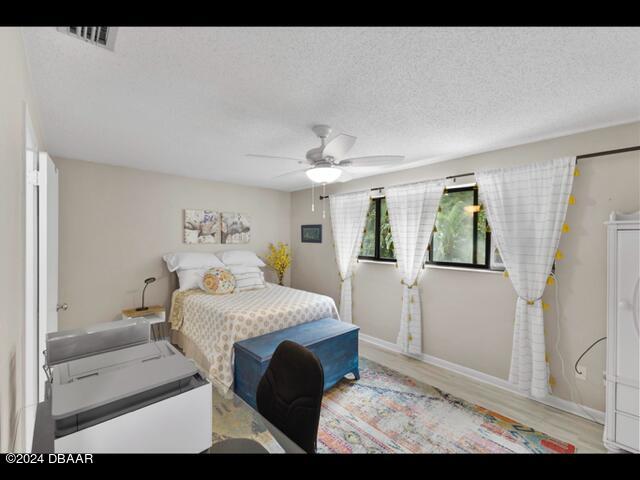 bedroom featuring ceiling fan, a textured ceiling, and light wood-type flooring