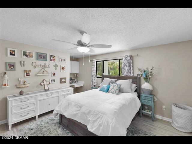 bedroom featuring hardwood / wood-style floors, a textured ceiling, and ceiling fan