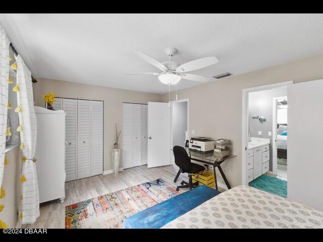 bedroom featuring multiple closets, ceiling fan, connected bathroom, and light hardwood / wood-style floors