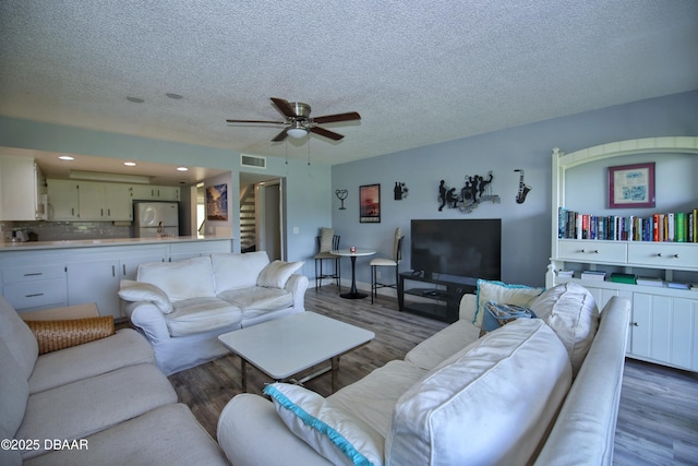 219 Club House Blvd Unit 219, New Smyrna Beach, FL 32168 - living room featuring wood finished floors, ceiling fan, a textured ceiling, baseboards, and stairway