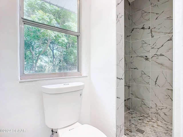 bathroom featuring tiled shower and toilet