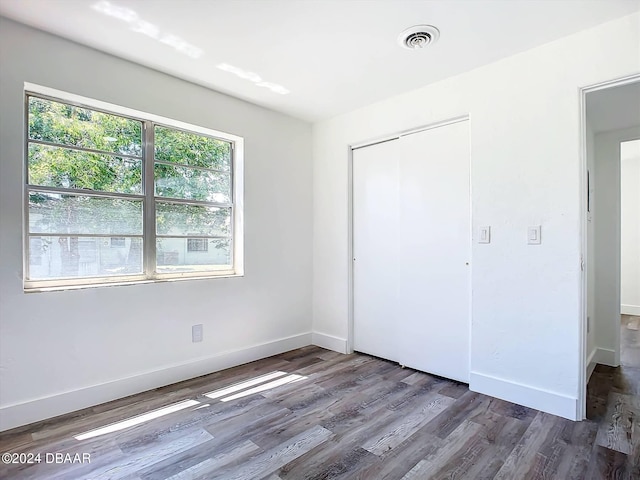 unfurnished bedroom with dark hardwood / wood-style flooring and a closet