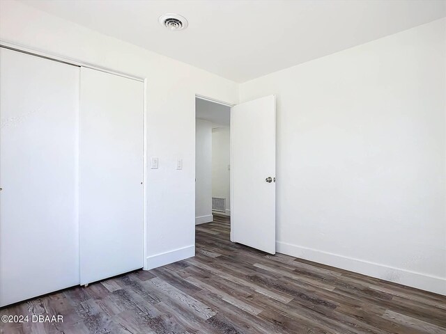 unfurnished bedroom featuring a closet and dark hardwood / wood-style floors