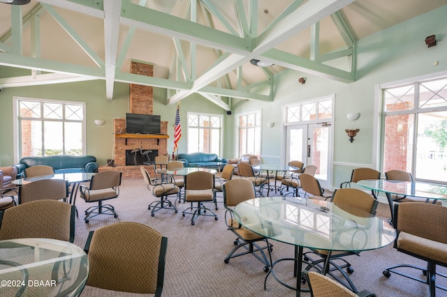 dining area with high vaulted ceiling, beam ceiling, carpet flooring, and a fireplace