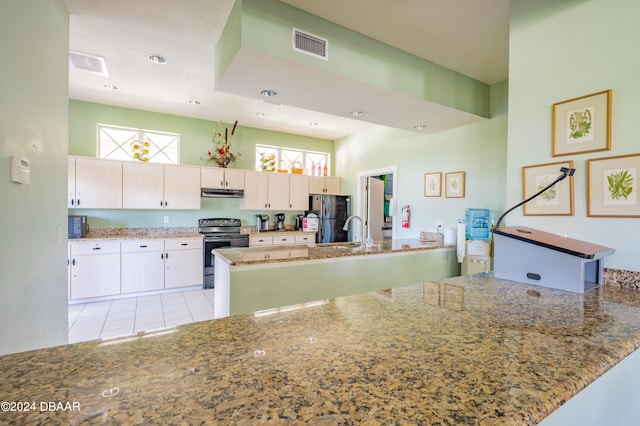 kitchen with black range with electric cooktop, a wealth of natural light, stainless steel fridge, and kitchen peninsula