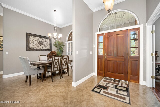 tiled entrance foyer featuring an inviting chandelier and ornamental molding