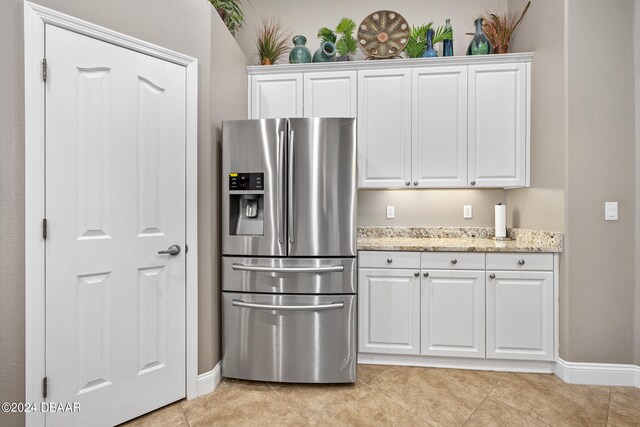 kitchen featuring stainless steel refrigerator with ice dispenser, light tile patterned flooring, and white cabinets