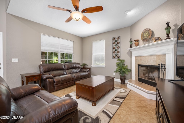 living room with light tile patterned flooring, ceiling fan, a tile fireplace, and a textured ceiling