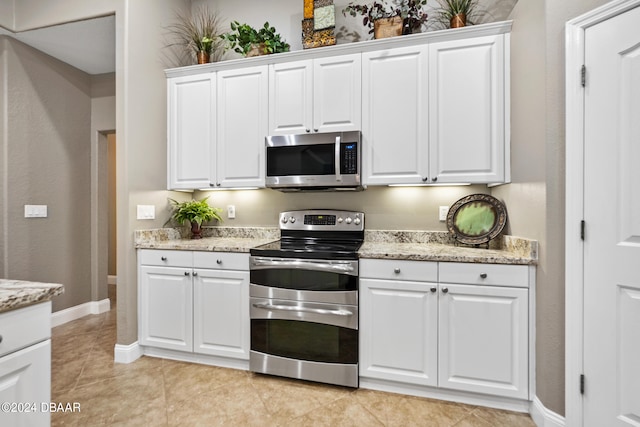 kitchen featuring white cabinets, appliances with stainless steel finishes, light tile patterned floors, and light stone counters