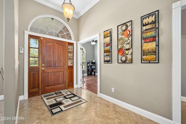 tiled entryway featuring plenty of natural light, ceiling fan, and crown molding