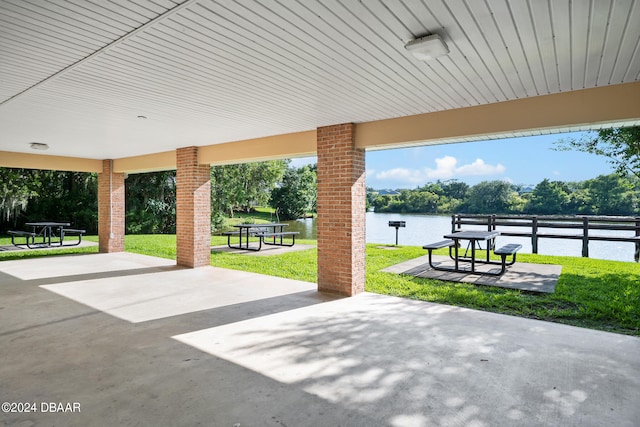 view of community with a water view, a lawn, and a patio area