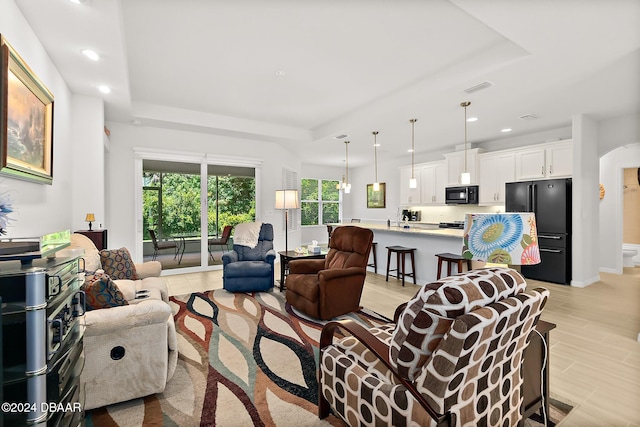 living room with light wood-type flooring and a tray ceiling