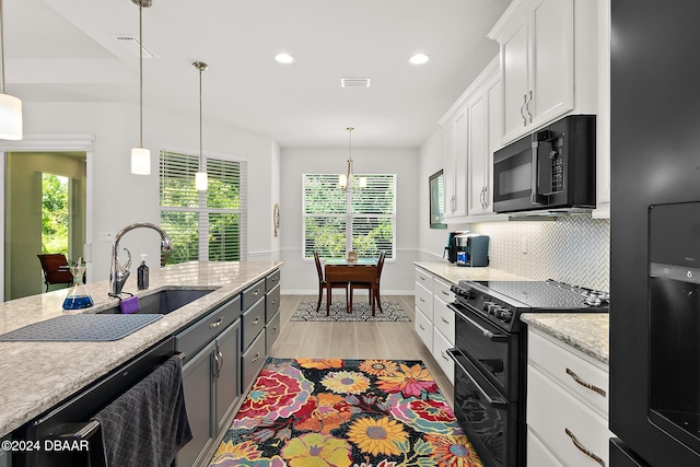 kitchen with black appliances, decorative light fixtures, light wood-type flooring, and white cabinetry