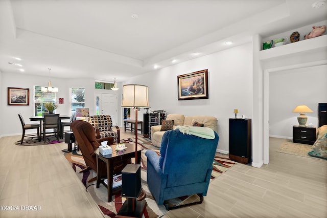 living room with a tray ceiling, light hardwood / wood-style flooring, and a notable chandelier