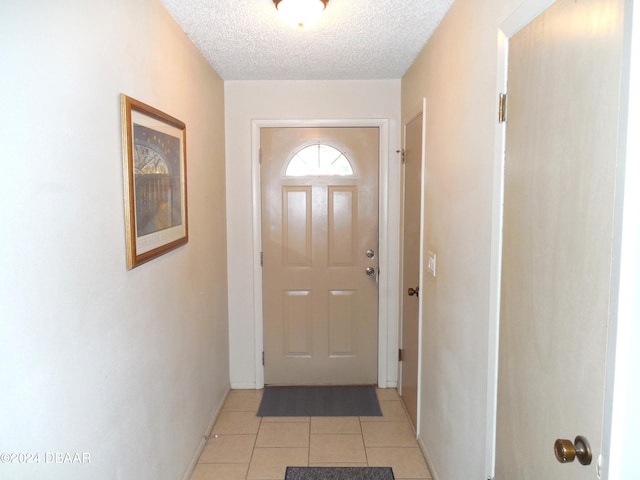 entryway with a textured ceiling and light tile patterned floors