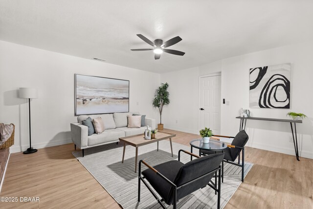 living area with light wood-style floors, visible vents, and ceiling fan
