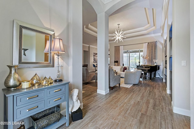 corridor featuring hardwood / wood-style flooring, crown molding, an inviting chandelier, and a tray ceiling