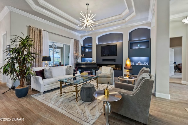 living room featuring crown molding, built in features, and a tray ceiling