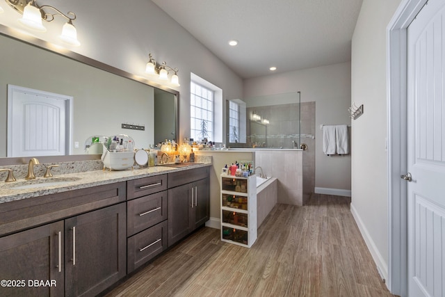 bathroom featuring wood-type flooring, vanity, and a tile shower