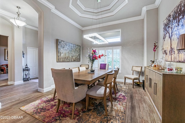 dining space featuring a tray ceiling, hardwood / wood-style floors, and crown molding