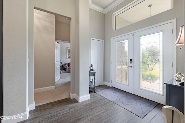 foyer with french doors, a healthy amount of sunlight, crown molding, and hardwood / wood-style floors