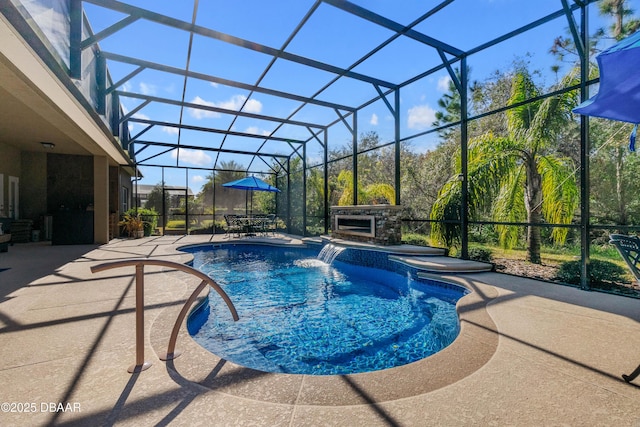 view of pool featuring an outdoor stone fireplace, glass enclosure, a patio area, a jacuzzi, and pool water feature