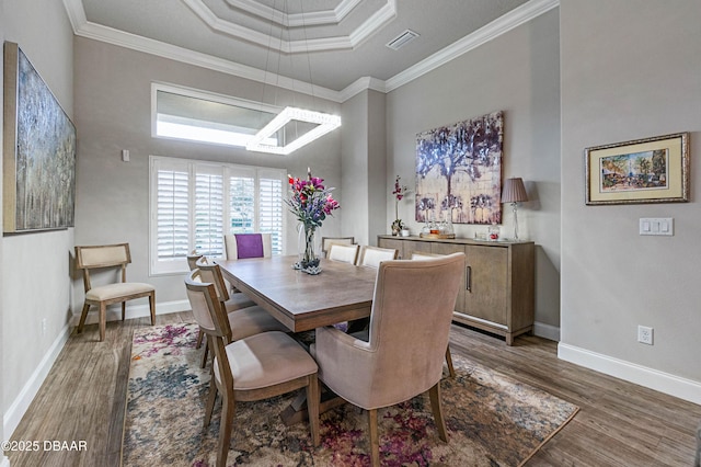 dining room featuring dark hardwood / wood-style flooring, crown molding, and a raised ceiling