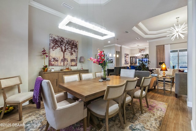 dining space featuring crown molding, a tray ceiling, hardwood / wood-style flooring, and a notable chandelier