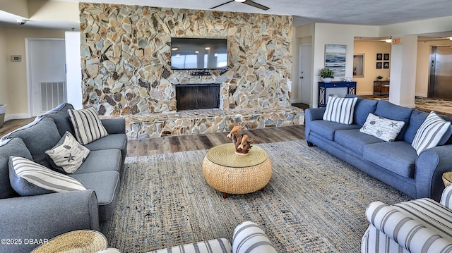 5499 S Atlantic Ave Unit 104, New Smyrna Beach, FL 32169 - living room featuring ceiling fan, visible vents, wood finished floors, elevator, and a fireplace