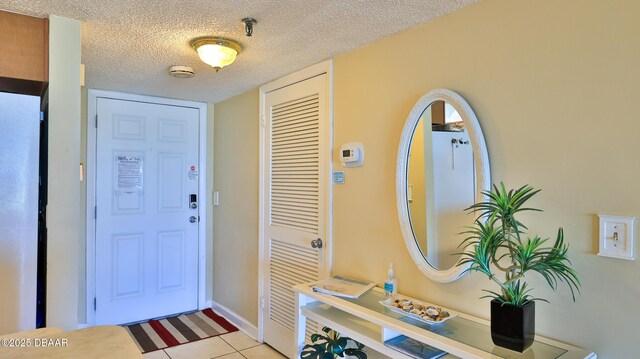 5499 S Atlantic Ave Unit 104, New Smyrna Beach, FL 32169 - entrance foyer featuring a textured ceiling, light tile patterned flooring, and baseboards