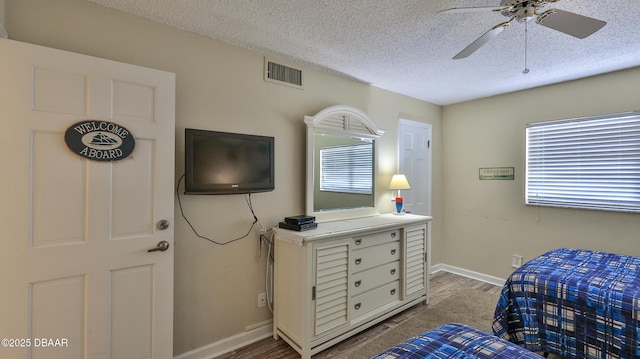 5499 S Atlantic Ave Unit 104, New Smyrna Beach, FL 32169 - bedroom featuring a textured ceiling, visible vents, baseboards, and wood finished floors