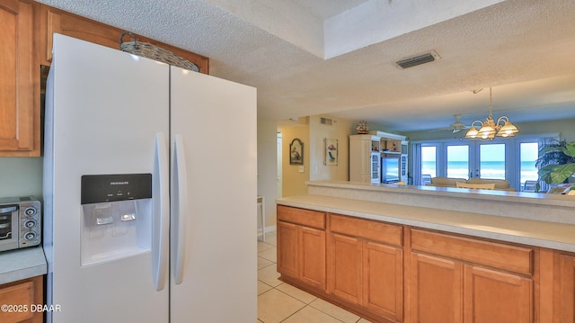 5499 S Atlantic Ave Unit 104, New Smyrna Beach, FL 32169 - kitchen featuring light countertops, light tile patterned floors, visible vents, and white fridge with ice dispenser