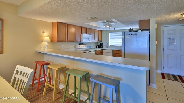 5499 S Atlantic Ave Unit 104, New Smyrna Beach, FL 32169 - kitchen featuring a peninsula, a textured ceiling, white appliances, and light countertops