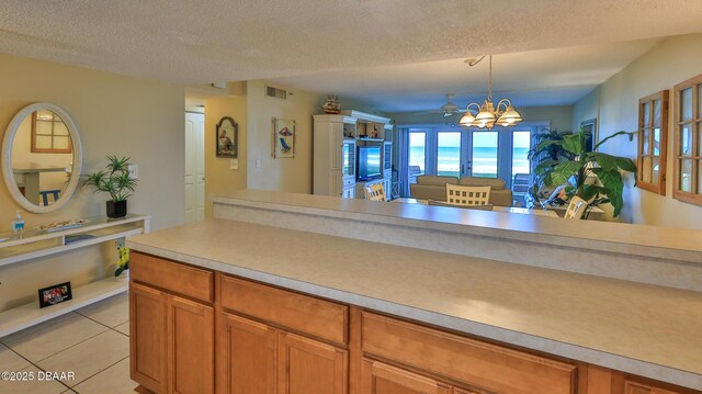 5499 S Atlantic Ave Unit 104, New Smyrna Beach, FL 32169 - kitchen featuring a textured ceiling, decorative light fixtures, an inviting chandelier, brown cabinets, and light countertops