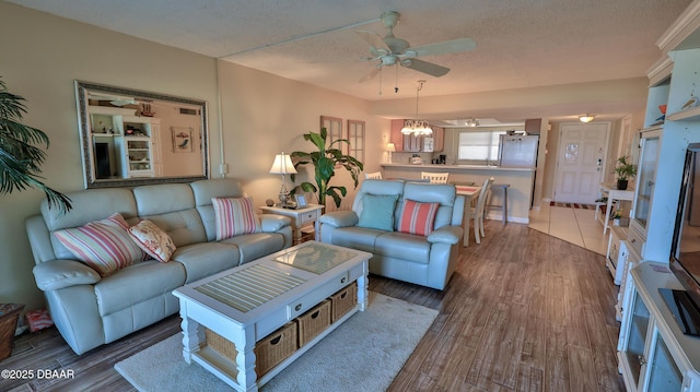 5499 S Atlantic Ave Unit 104, New Smyrna Beach, FL 32169 - living area featuring wood finished floors, a textured ceiling, and ceiling fan with notable chandelier