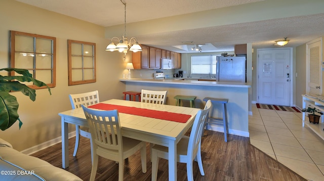 5499 S Atlantic Ave Unit 104, New Smyrna Beach, FL 32169 - dining area featuring a textured ceiling, baseboards, a notable chandelier, and light wood-style floors
