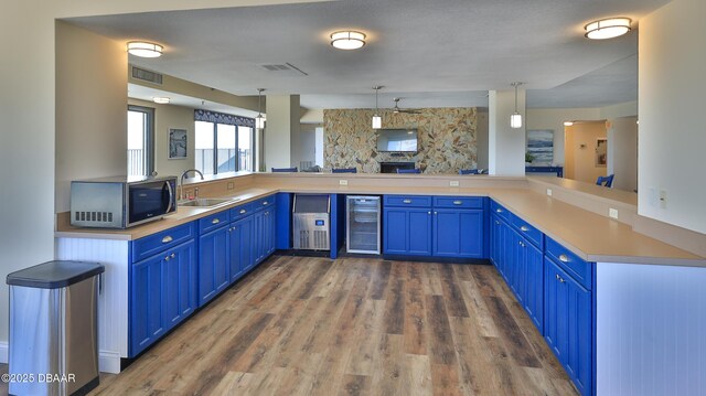 5499 S Atlantic Ave Unit 104, New Smyrna Beach, FL 32169 - kitchen featuring beverage cooler, a sink, stainless steel microwave, blue cabinets, and dark wood-style floors