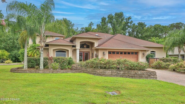 1929 Spruce Creek Lndg, Port Orange, FL 32128 - mediterranean / spanish-style house featuring stucco siding, a garage, a front lawn, and driveway