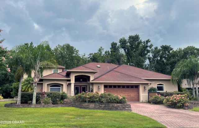 1929 Spruce Creek Lndg, Port Orange, FL 32128 - mediterranean / spanish home featuring a garage, stucco siding, a front lawn, and decorative driveway