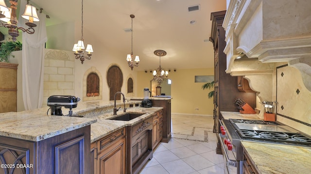 1929 Spruce Creek Lndg, Port Orange, FL 32128 - kitchen featuring gas range, a chandelier, light tile patterned floors, an island with sink, and a high ceiling