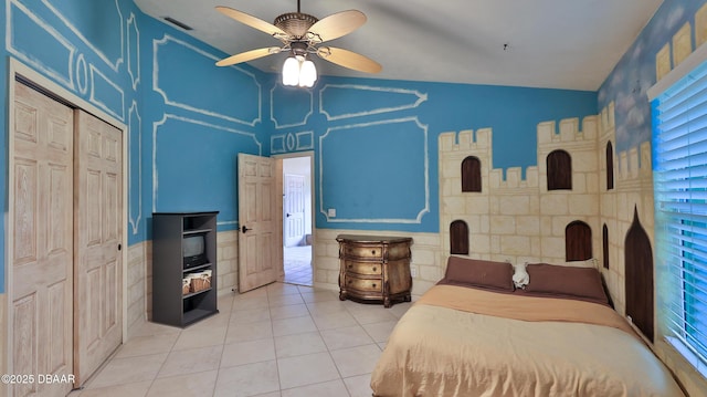 1929 Spruce Creek Lndg, Port Orange, FL 32128 - bedroom featuring lofted ceiling, light tile patterned flooring, ceiling fan, a wainscoted wall, and a closet