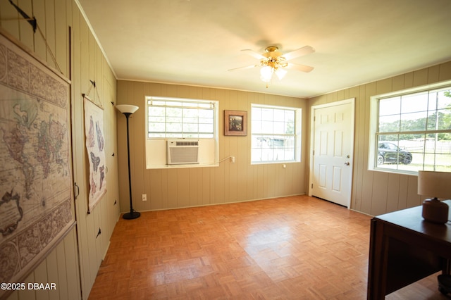 foyer with baseboards, wood walls, cooling unit, and ceiling fan