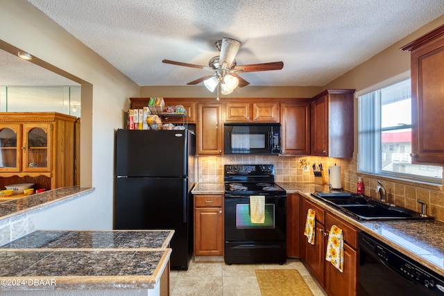 kitchen with backsplash, black appliances, sink, light tile patterned floors, and a textured ceiling